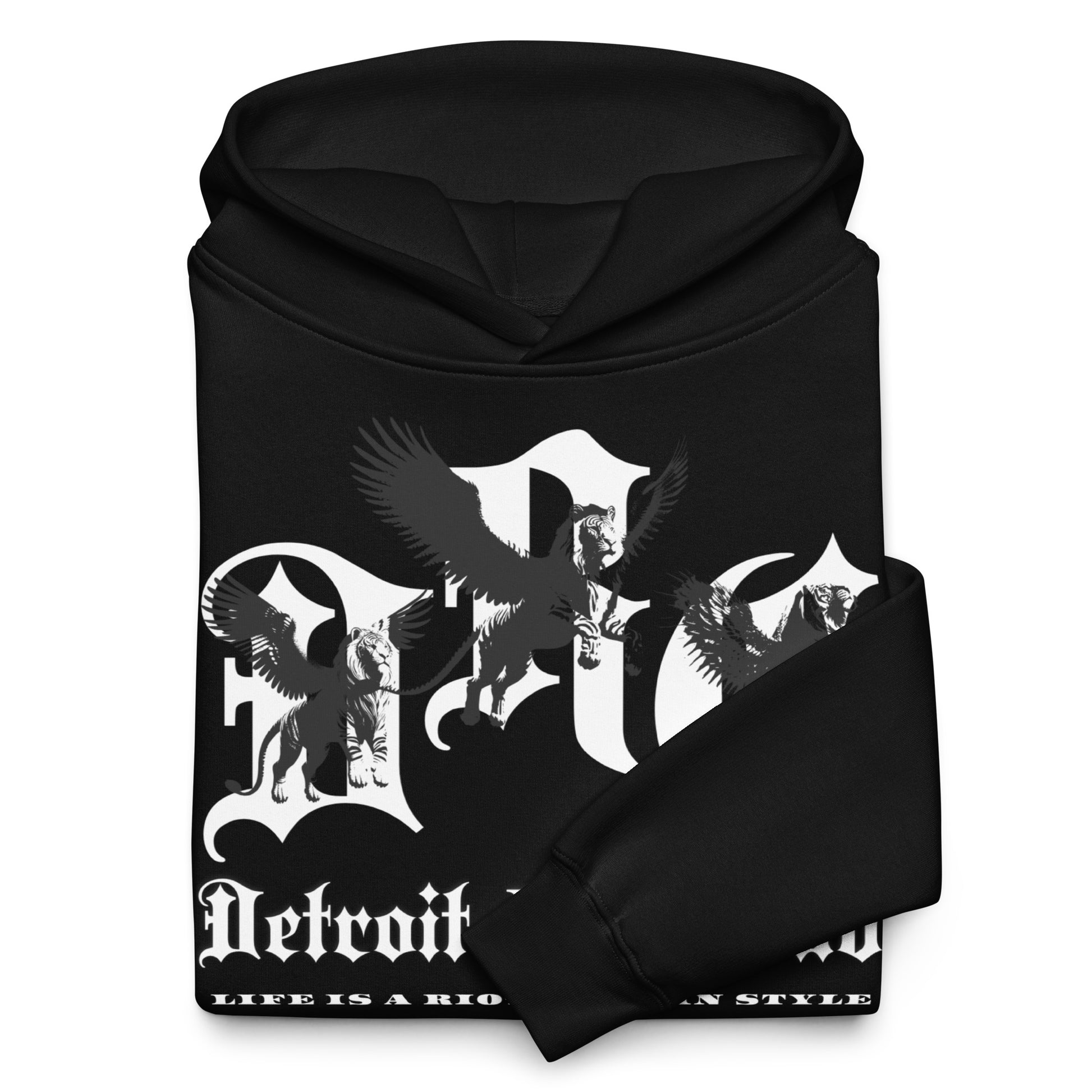 "Close-up detail of the Legacy Crest archival branding neatly folded with one sleeve flipped over the front design. Showcases the 'Strength Through Quality Garments' commitment and crisp white ink on Void Black hardware."