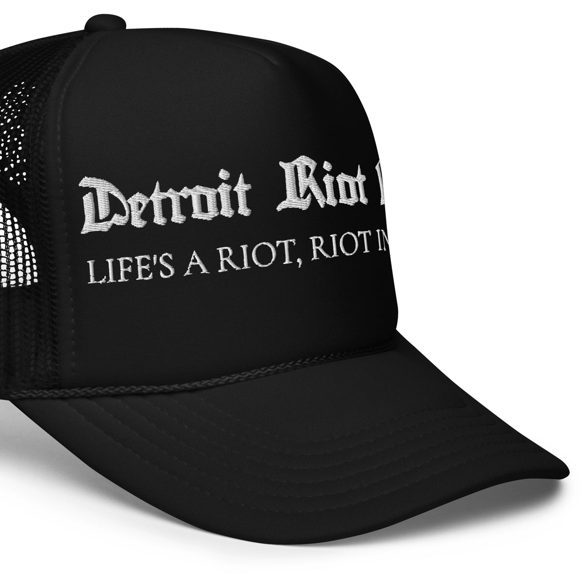 "Right-side crown detail of the Detroit Riot Club Motto Foam Trucker in black, highlighting the archival gothic embroidery, structured foam front, and mesh side panel construction."